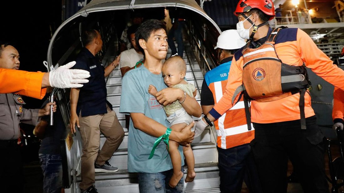 A passenger carrying a baby arrives after KMP Mutiara Sentosa 2 ferry caught fire in the waters off Madura Island, at the Gapura Surya Nusantara port terminal after being evacuated, in Surabaya, East Java province, Indonesia, August 3, 2026. REUTERS/