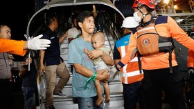 A passenger carrying a baby arrives after KMP Mutiara Sentosa 2 ferry caught fire in the waters off Madura Island, at the Gapura Surya Nusantara port terminal after being evacuated, in Surabaya, East Java province, Indonesia, August 3, 2026. REUTERS/