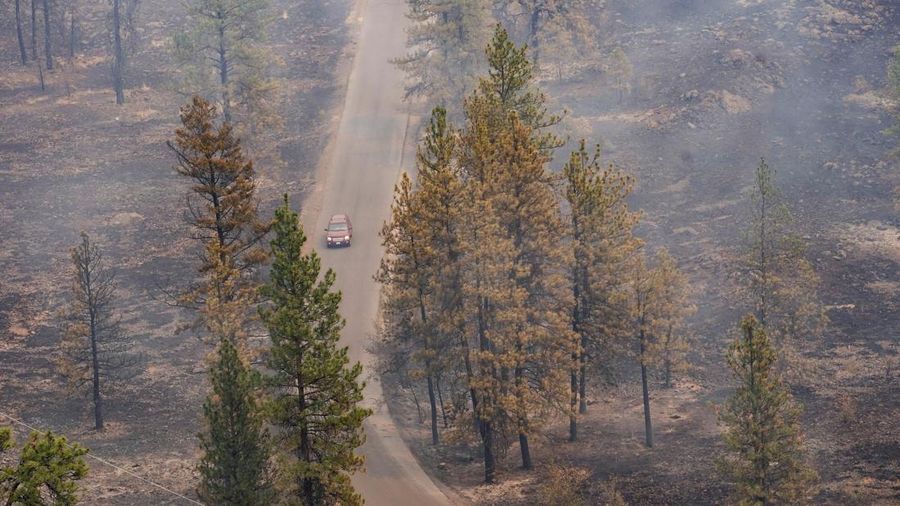 Sebuah kendaraan melintas saat asap mengepul dari Kebakaran Old Trails ketika kebakaran rimba melanda Spokane, Washington, AS, 2 Agustus 2026.