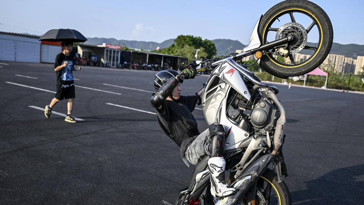 This picture taken on July 21, 2026 shows a man practising riding a motorcycle at a club in Chongqing, southwestern China. The roar of engines fills the night air in China's Chongqing city as tourists awkwardly clamber onto gleaming motorbikes and cl