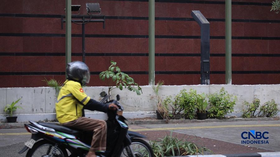 Warga melintas di samping pagar Blok M Plaza, Jakarta, Senin (3/8/2026). Polemik pemasangan pagar tinggi di sejumlah pusat perbelanjaan di Jakarta mencuri perhatian setelah beberapa mal memasang pagar besi nan mengelilingi area bangunan. (CNBC Indon
