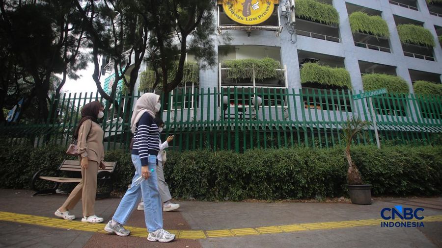 Warga melintas di samping pagar Blok M Plaza, Jakarta, Senin (3/8/2026). Polemik pemasangan pagar tinggi di sejumlah pusat perbelanjaan di Jakarta mencuri perhatian setelah beberapa mal memasang pagar besi nan mengelilingi area bangunan. (CNBC Indon