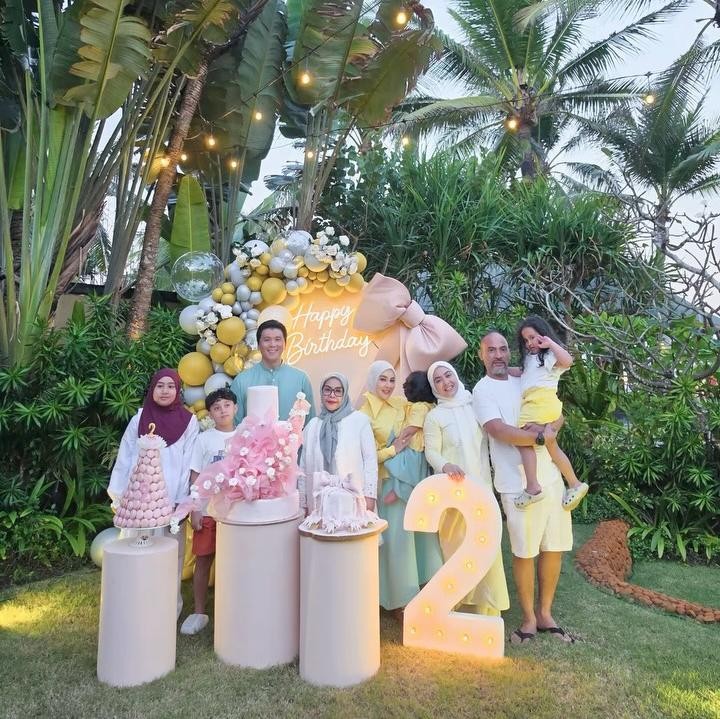 <p>Pesta ulang tahun juga turut dihadiri oleh keluarga besar Syahrini, termasuk ibundanya, Wati Nurhayati dan saudara perempuannya, Aisyahrani. Keluarga ini terlihat mengabadikan momen ulang tahun 'Baby R' di dekat kue ulang tahun dan <em>backdrop</em>&nbsp;dekorasi serba kuning. (Foto: Instagram @princessyahrini)</p>