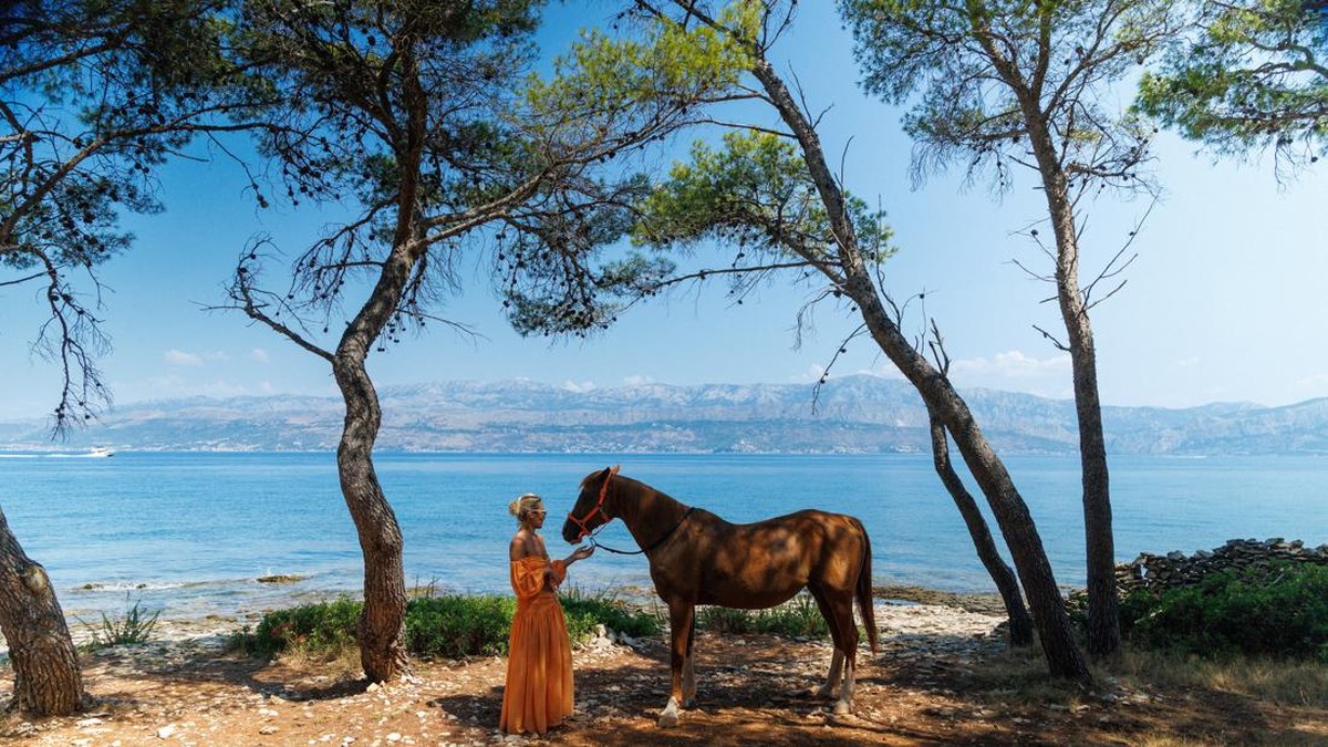 A woman poses for a picture with a horse named 'Providenca' after swimming with a horse during a heatwave in Supetar on the island of Brac, Croatia, August 5, 2026. REUTERS/Antonio Bronic