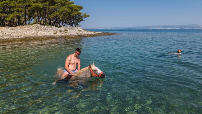 A man rides a horse named 'Perlaz' in the water during a heatwave in Supetar on the island of Brac, Croatia, August 5, 2026. REUTERS/Antonio Bronic
