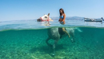 Lara Grbac, 14, rides a horse named 'Perlaz' in the water during a heatwave in Supetar on the island of Brac, Croatia, August 5, 2026. REUTERS/Antonio Bronic