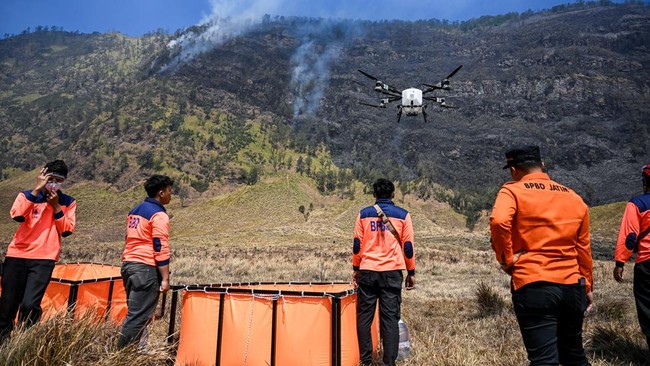 Officials from the East Java Provincial Disaster Management Agency fly a drone carrying water to battle a wildfire in the Bromo Tengger Semeru National Park near Mount Bromo in Probolinggo, East Java province on August 6, 2026. (Photo by JUNI KRISWAN
