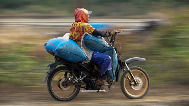 A worker uses a motorbike to transport sacks of freshly harvested salt in Pengarengan village, Cirebon, West Java province, Indonesia, July 30, 2026. REUTERS/Willy Kurniawan