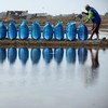 A farmer packs sacks of salt on a dyke during harvest at a salt pond in Pengarengan village, Cirebon, West Java province, Indonesia, July 30, 2026. REUTERS/Willy Kurniawan
