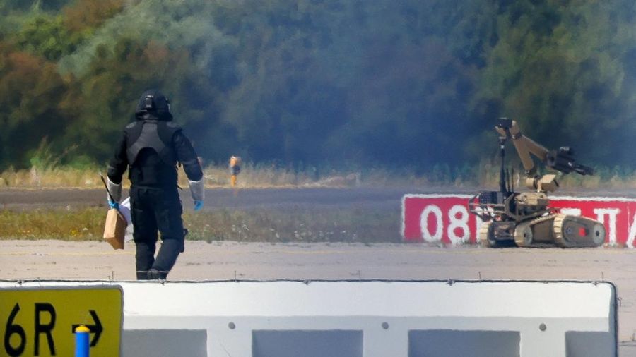 Seorang petugas polisi nan mengenakan busana pelindung melangkah di samping robot penjinak bahan peledak (EOD) di Bandara Leipzig/Halle di Schkeuditz, Jerman, pada 5 Agustus 2026. Langkah ini diambil setelah polisi menyatakan bahwa mahir bahan peledak telah memeriksa sebuah pesawat nirawak (drone) nan ditemukan di dekat landasan pacu, serta menyusul kejadian pesawat kargo DHL nan menabrak objek tak dikenal saat sedang menanjak meninggalkan airport pada malam sebelumnya, nan memicu pendaratan tak teragendakan di Hanover, menurut sumber nan mengetahui peristiwa tersebut.