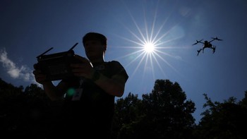 Hwang Han-jae, a public servant from the Safety and Administration Office of Gyeongsangbuk-do Provincial Government, flies a drone equipped with loudspeakers and thermal imaging camera over a chilli pepper field during a heat wave warning in Andong,