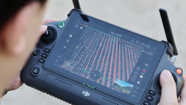 Hwang Han-jae, a public servant from the Safety and Administration Office of Gyeongsangbuk-do Provincial Government, checks the temperature of a plastic greenhouse through a drone equipped with loudspeakers and thermal imaging camera over a chilli pe