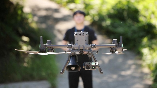 Hwang Han-jae, a public servant from the Safety and Administration Office of Gyeongsangbuk-do Provincial Government, flies a drone equipped with loudspeakers and thermal imaging camera over a chilli pepper field during a heat wave warning in Andong,
