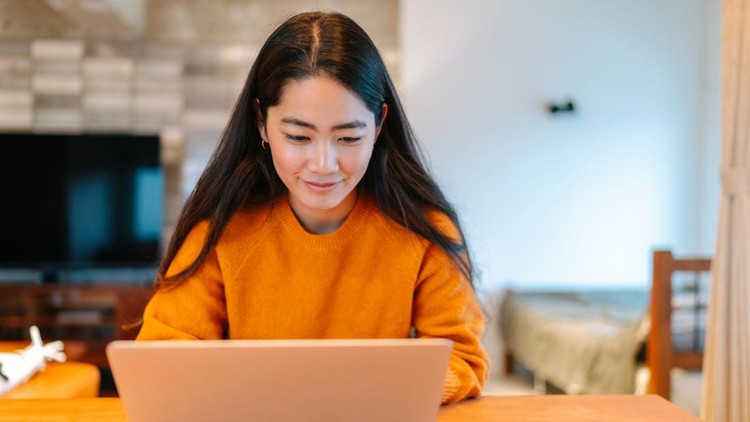 A young stylish woman is sitting at a table and using a laptop in the living room at home&period;
