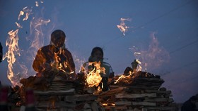 People watch ritual offerings being consumed by fire during ceremonies for the Month of Pachamama, as Bolivians make offerings to Mother Earth to seek health, prosperity and good harvests, in La Cumbre, on the outskirts of La Paz, Bolivia, August 1,