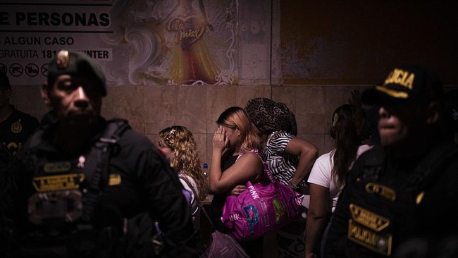 Sex workers wait to undergo an identity check during an anti-human trafficking police operation called Sodom and Gomorrah at La Miel brothel, in the Independencia district, on the northern outskirts of Lima on July 31, 2026 late night. (Photo by ERNE