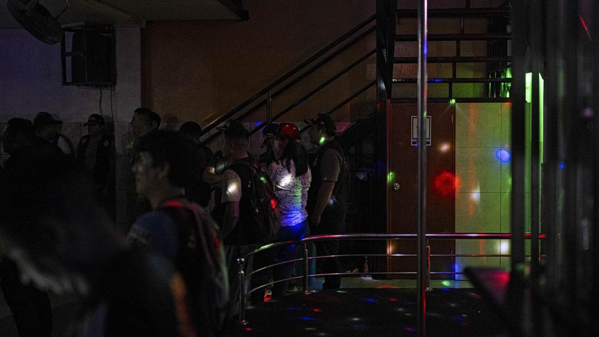 Sex workers wait to undergo an identity check during an anti-human trafficking police operation called Sodom and Gomorrah at La Miel brothel, in the Independencia district, on the northern outskirts of Lima on July 31, 2026 late night. (Photo by ERNE