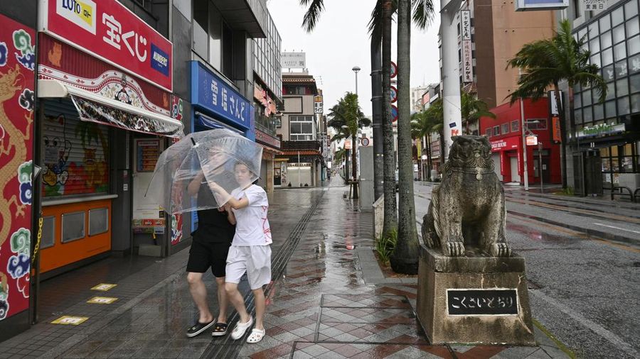 Orang-orang melangkah membawa payung di Naha, Prefektur Okinawa, Jepang, pada 7 Agustus 2026. (Kyodo/via REUTERS)