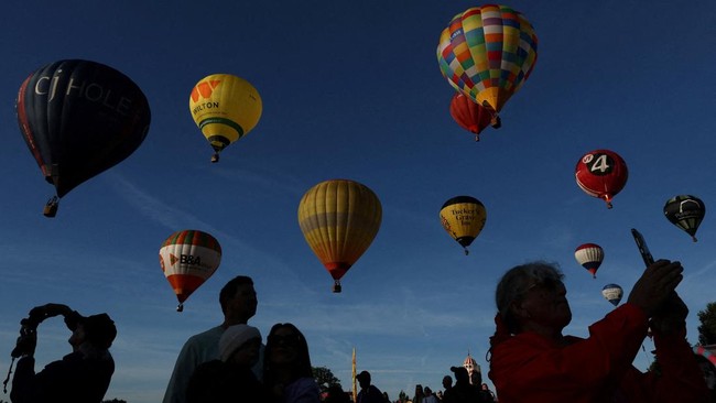 People watch hot air balloons fly during a mass launch at the annual Bristol International Balloon Fiesta, Bristol, Britain, August 8, 2026. REUTERS/Toby Melville