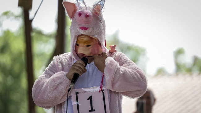 A participant in the French pig-squealing championship performs on stage at the 43rd edition of the Pig Festival, in Trie-sur-BaÔse, south-western France, on August 9, 2026. (Photo by Valentine CHAPUIS / AFP)