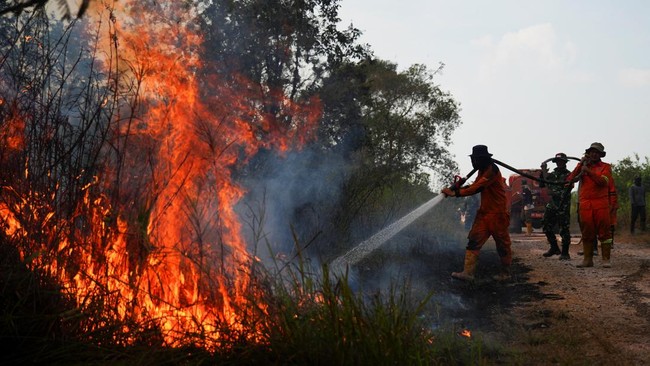 Firefighters and military personnel, help to spray water in an attempt to extinguish fire at an area affected by wildfire in Ogan Ilir regency, South Sumatra province, Indonesia, August 9, 2026. REUTERS/Abriansyah Liberto