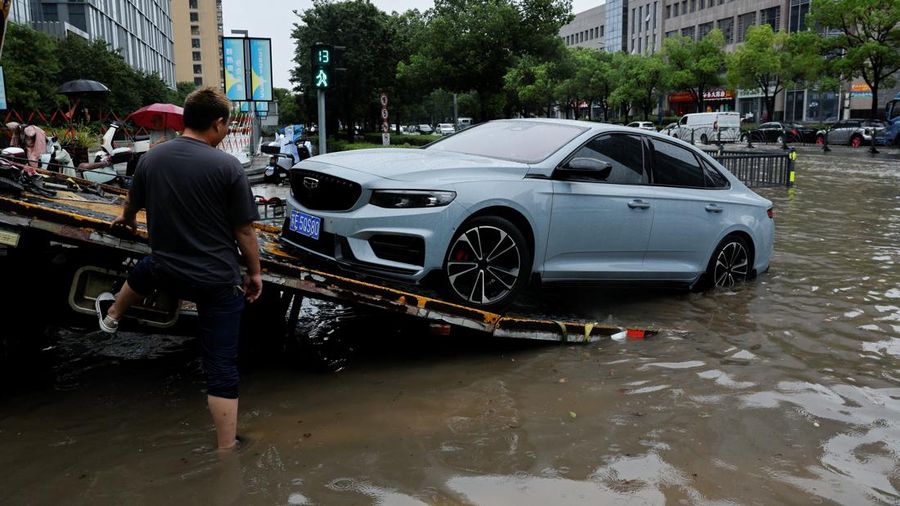 Seorang pekerja meningkatkan mobil nan mogok ke atas truk pengangkut mobil di jalan nan tergenang air setelah Topan Dolphin membawa hujan lebat ke Shanghai, Tiongkok, pada 10 Agustus 2026.