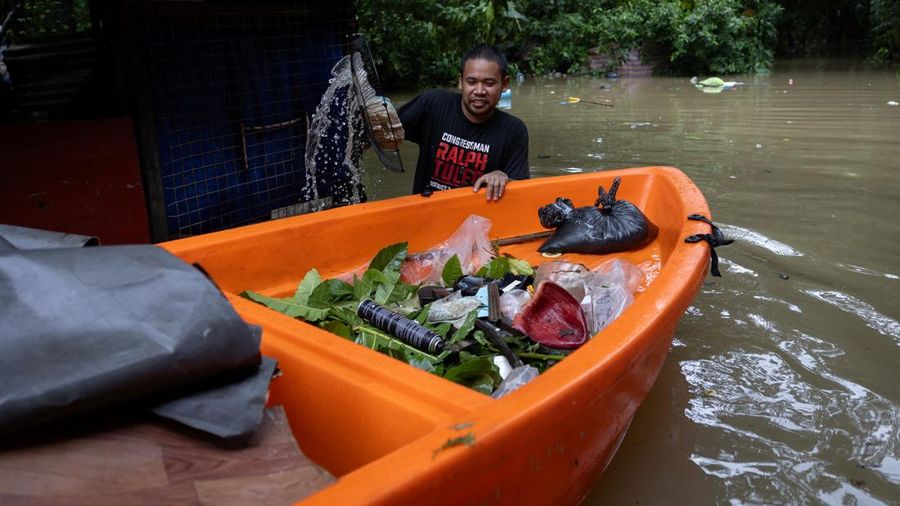Seorang laki-laki mengumpulkan sampah menggunakan perangkat penyaring darurat di sebuah desa nan terendam banjir akibat hujan monsun barat daya di Bagong Silangan, Quezon City, Filipina, pada 10 Agustus 2026.