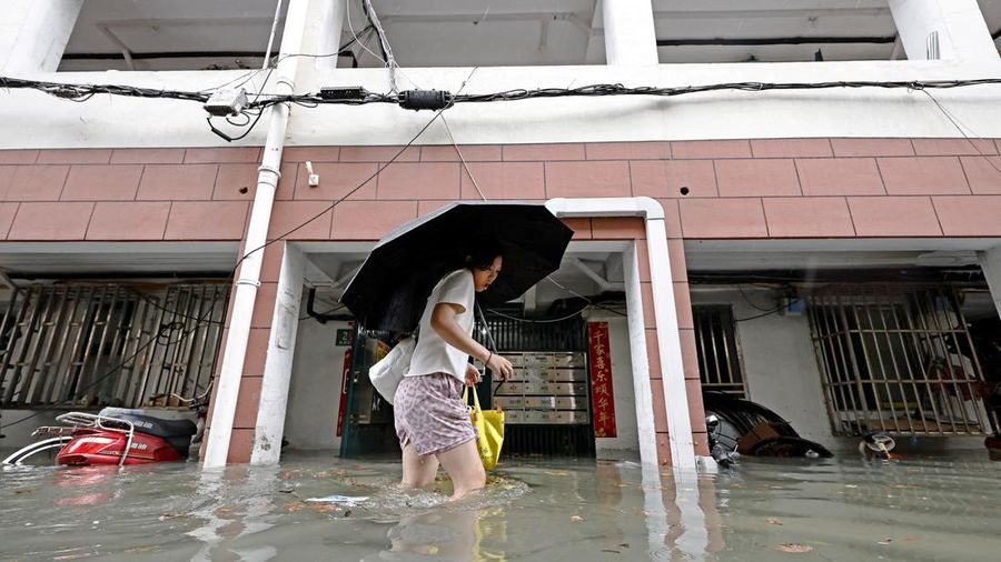 Seorang penduduk menerjang banjir di sebuah kompleks perumahan setelah hujan deras saat Topan Dolphin mendekat, di Shanghai, Tiongkok, 9 Agustus 2026.
