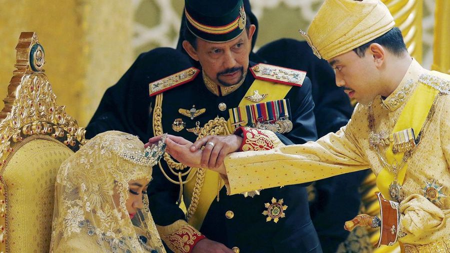 Sultan Brunei Hassanal Bolkiah memegang lengan putranya Pangeran Abdul Malik untuk memberkati istri baru Malik, Dayangku Raabi'atul 'Adawiyyah Pengiran Haji Bolkiah saat