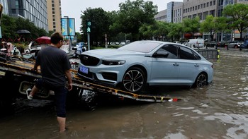 A worker loads a broken-down car onto a car carrier truck on a flooded street after Typhoon Dolphin brought heavy rain to Shanghai, China, August 10, 2026. REUTERS/Go Nakamura