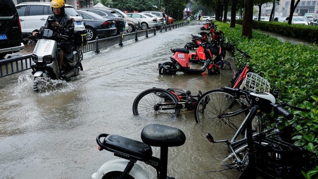 A person rides an electric bike through a flooded street after Typhoon Dolphin brought heavy rain to Shanghai, China, August 10, 2026. REUTERS/Go Nakamura