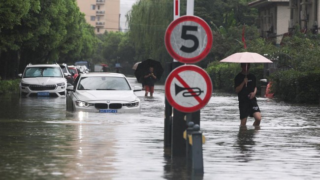 People wade through a flooded street after Typhoon Dolphin brought heavy rain to Shanghai, China, August 10, 2026. REUTERS/Go Nakamura