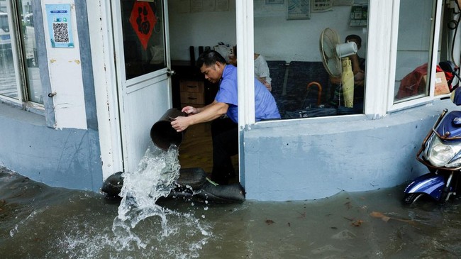 A person uses a bucket to remove water from a flooded room after Typhoon Dolphin brought heavy rain to Shanghai, China, August 10, 2026. REUTERS/Go Nakamura