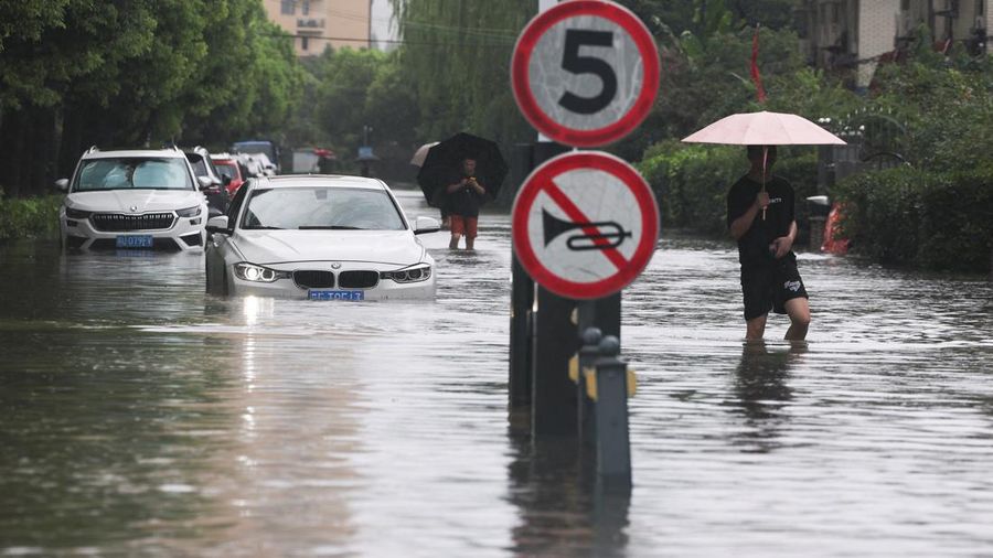 Warga melangkah menerjang jalanan nan tergenang banjir setelah Topan Dolphin membawa hujan lebat ke Shanghai, Tiongkok, pada 10 Agustus 2026.