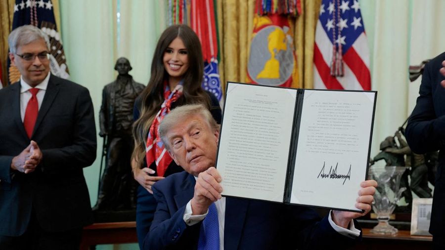 Presiden AS Donald Trump memperlihatkan perintah pelaksana nan telah ditandatangani mengenai elastisitas vaksin, dengan Dr. Jay Bhattacharya, Direktur National Institutes of Health, berdiri di belakangnya, di Ruang Oval Gedung Putih di Washington, D.C., AS, pada 10 Agustus 2026.