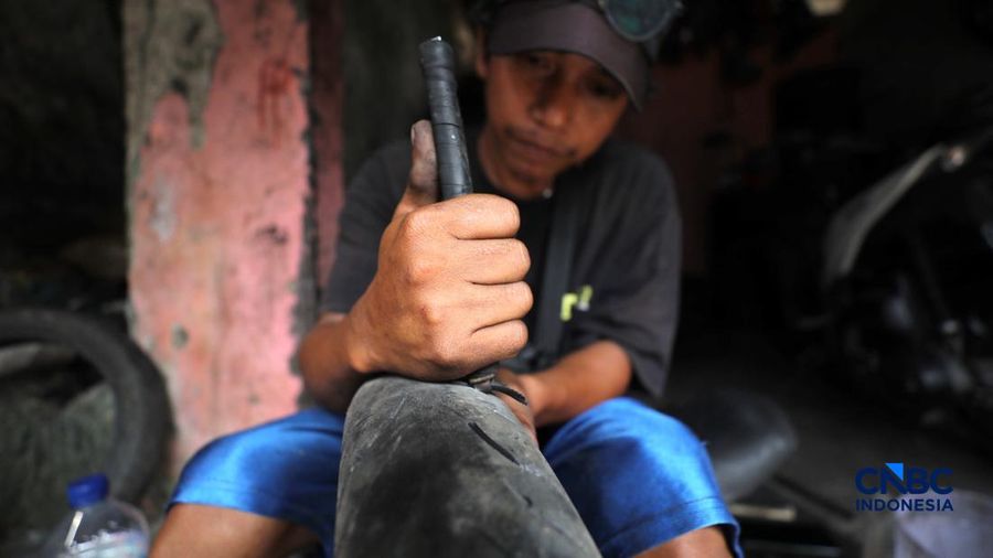 Seorang pekerja menyelesaikan pengerikan ulang ban motor jejak (Vulkanisir) di Kawasan Beji, Depok, Jawa Barat, Selasa (11/8/2026). (CNBC Indonesia/Tri Susilo)
