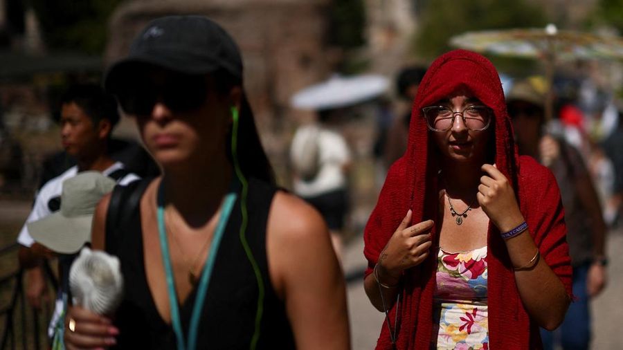 Seorang wanita menutupi kepalanya untuk berlindung dari sinar mentari saat mengunjungi Forum Romawi di tengah suhu nan mendekati 40 derajat Celsius akibat gelombang panas, di Roma, Italia, 11 Agustus 2026.