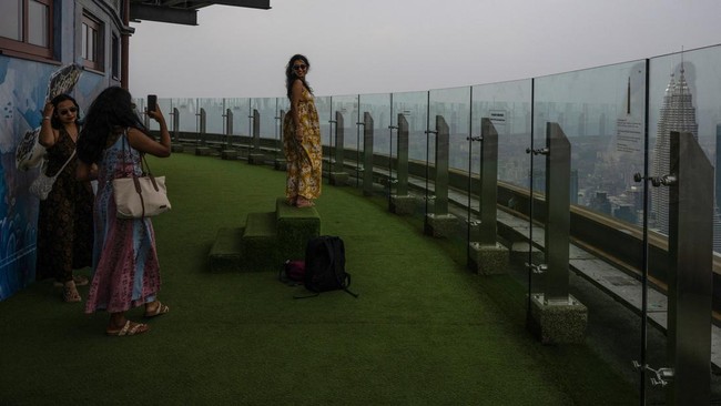 Visitors take pictures from the KL Tower as the city skyline is covered in haze in Kuala Lumpur on August 11, 2026, as authorities in Malaysia warned of high levels of air pollution from regional wildfires. The Malaysian Meteorological Department urg