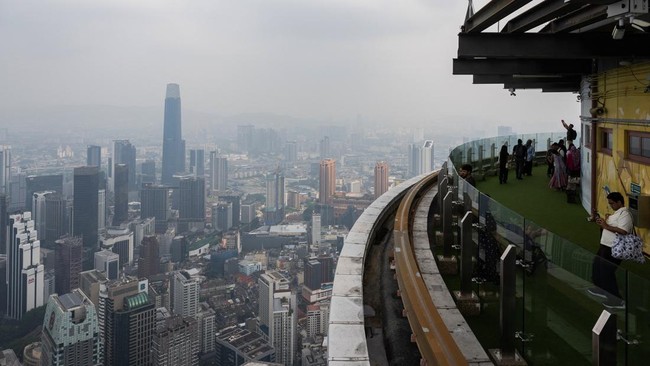 Visitors take pictures from the Kl Tower as the city is covered in haze in Kuala Lumpur on August 11, 2026, as authorities in Malaysia warned of high levels of air pollution from regional wildfires. The Malaysian Meteorological Department urged peopl