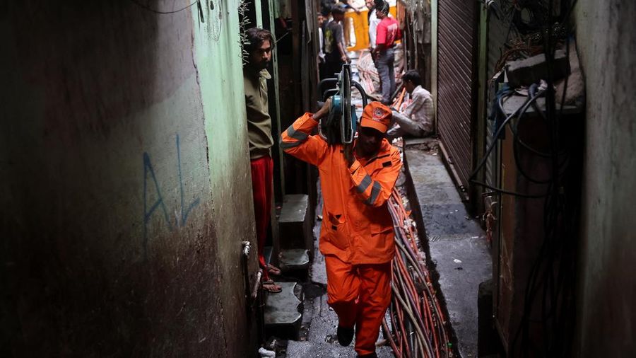 Seorang personel Pasukan Tanggap Bencana Nasional (NDRF) membawa peralatan pemotong sembari melangkah menuju letak tanah longsor, setelah sebagian bukit runtuh menimpa rumah-rumah di area permukiman padat masyarakat di Mumbai, India, pada 12 Agustus 2026.
