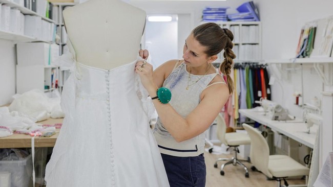 Designer Kat Eberley works on a dress at the Jenny Yoo bridal boutique in New York City, U.S., August 6, 2026. REUTERS/Jeenah Moon