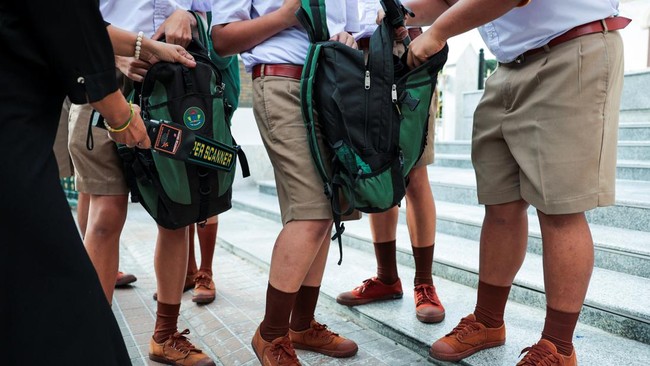 A teacher and a student prefect use metal detectors to screen for weapons, and check students' bags as they enter a school in Bangkok, following a deadly shooting at Debsirin Nonthaburi School in Nonthaburi province on the outskirts of Bangkok, Thail