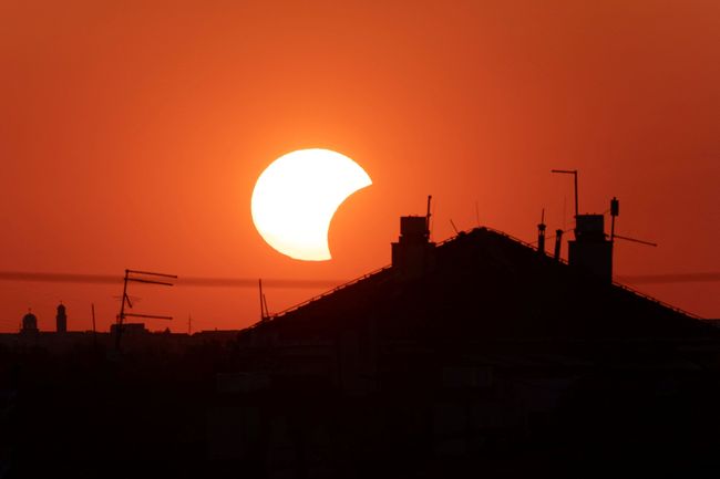Bulan menutupi sebagian Matahari di atas sebuah atap saat gerhana matahari, sebagaimana terlihat dari Beograd, Serbia, pada 12 Agustus 2026.