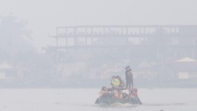 Sejumlah pelajar berangkat sekolah menggunakan perahu tradisional melewati kawasan yang diselimuti kabut asap di Sungai Ogan, Palembang, Sumatera Selatan, Kamis (13/8/2026). Kabut asap tersebut merupakan dampak dari kebakaran hutan dan lahan (Karhutl