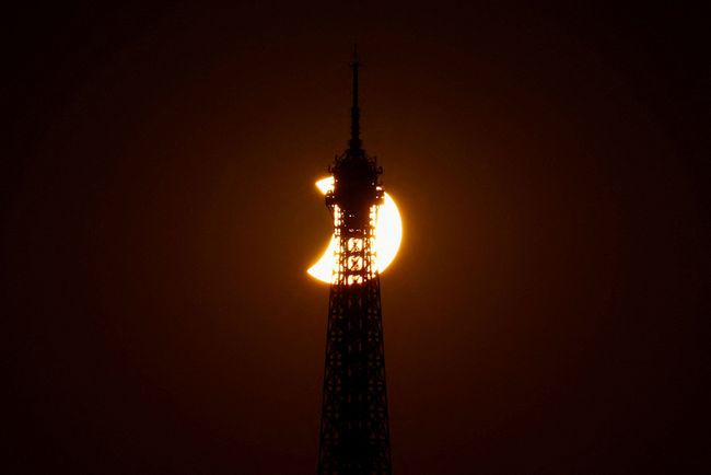 Menara Eiffel tampak dalam siluet saat bulan menutupi sebagian matahari selama gerhana matahari, sebagaimana terlihat dari Paris, Prancis, pada 12 Agustus 2026.