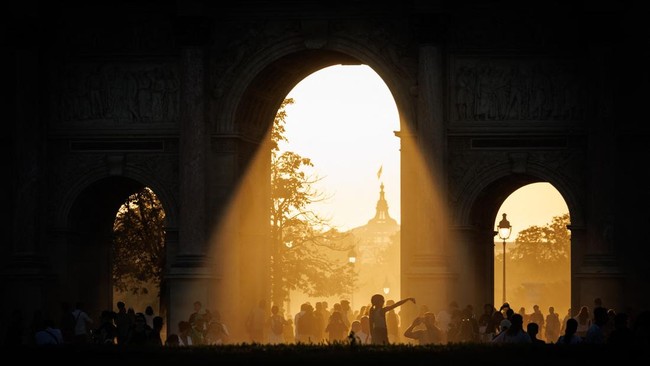 Attendees watch as the moon fully passes over the sun's horizon during a partial solar eclipse at the Arc de Triomphe du Carrousel in Paris on August 12, 2026. In France, the solar eclipse was not total - after the total solar eclipse of 1999 France