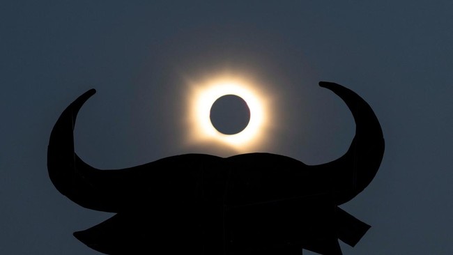The moon completely covers the sun during a solar eclipse near the silhouette of an Osborne Bull, in Navarrete, northern Spain, August 12, 2026. REUTERS/Vincent West