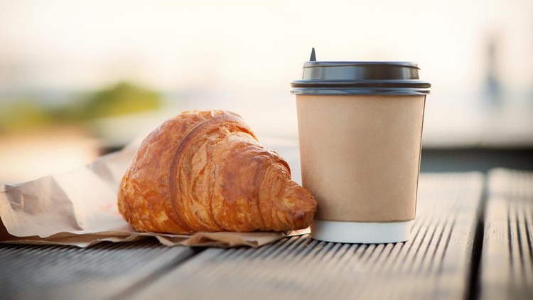 eco paper cup with coffee or tea and croissant on kraft paper&comma; on a wooden table&period; Breakfast on the street&comma; in the park