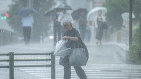 People walk along a street in heavy rain in Tokyo on July 24, 2026. (Photo by Yuichi YAMAZAKI / AFP)