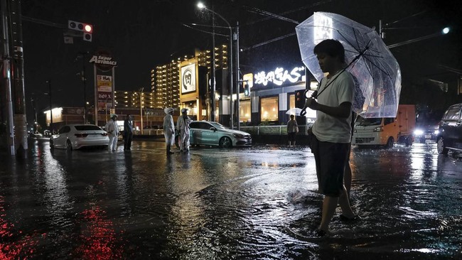 A man walks on a flooded road after torrential rain in Ichikawa, Chiba Prefecture, Japan, August 13, 2026. Kyodo/via REUTERS ATTENTION EDITORS - THIS IMAGE WAS PROVIDED BY A THIRD PARTY. EDITORIAL USE ONLY. MANDATORY CREDIT. JAPAN OUT. NO COMMERCIAL